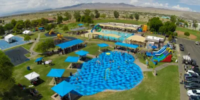 Aerial view of Ken Fovargue Park shows splash pad, two playgrounds, city pool, two softball fields, parking lot, and two large inflatable water slides.