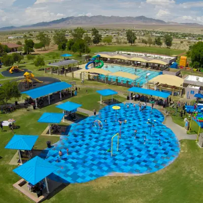 Aerial view of Ken Fovargue Park shows splash pad, two playgrounds, city pool, two softball fields, parking lot, and two large inflatable water slides.