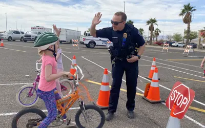Police officer high fiving a child riding a bicycle with a helmet