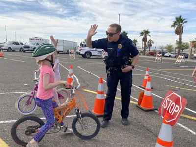 Police officer high fiving a child riding a bicycle with a helmet