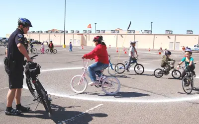 officer helping children ride a bicycle safety course