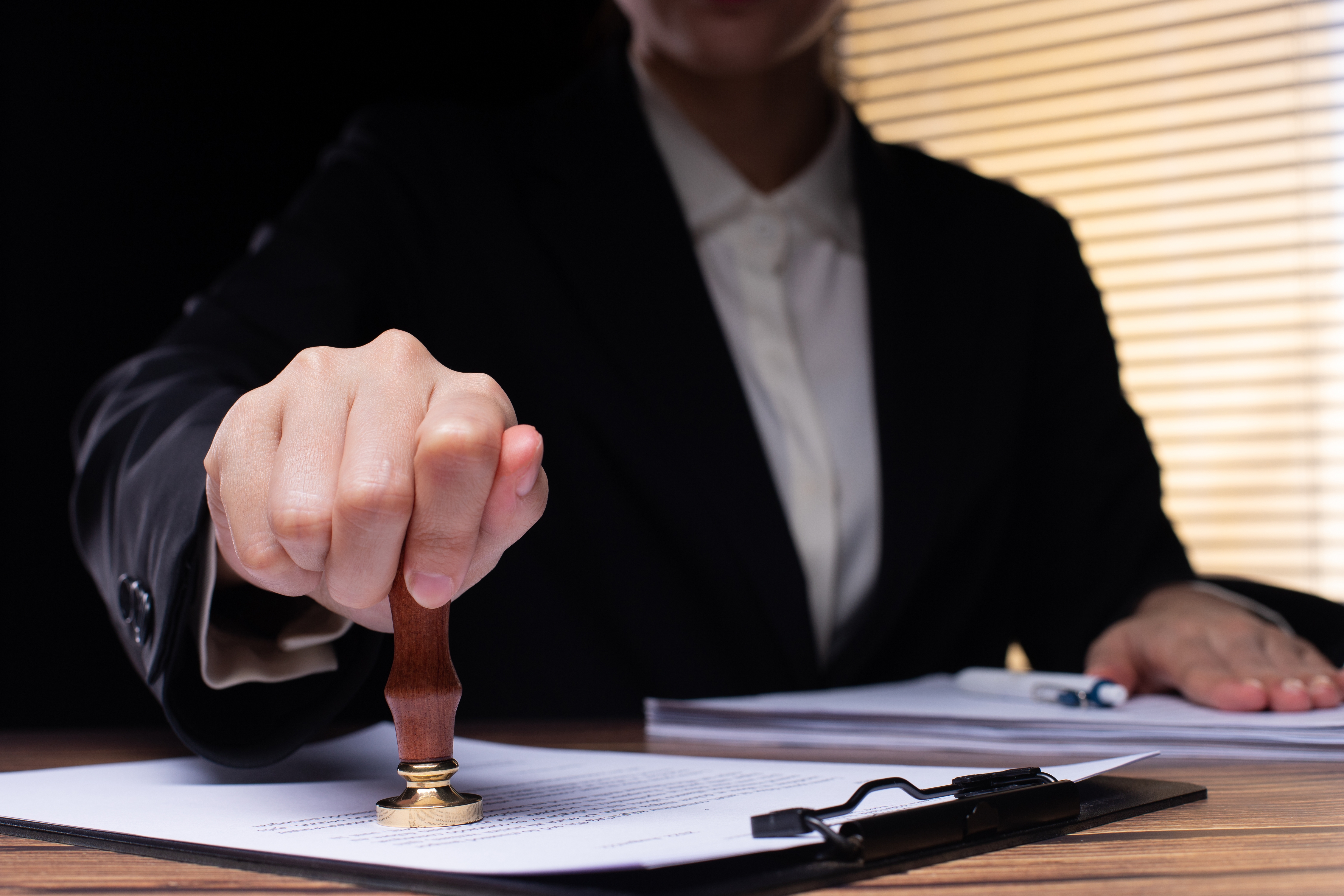 Hand places official stamp of approval on document